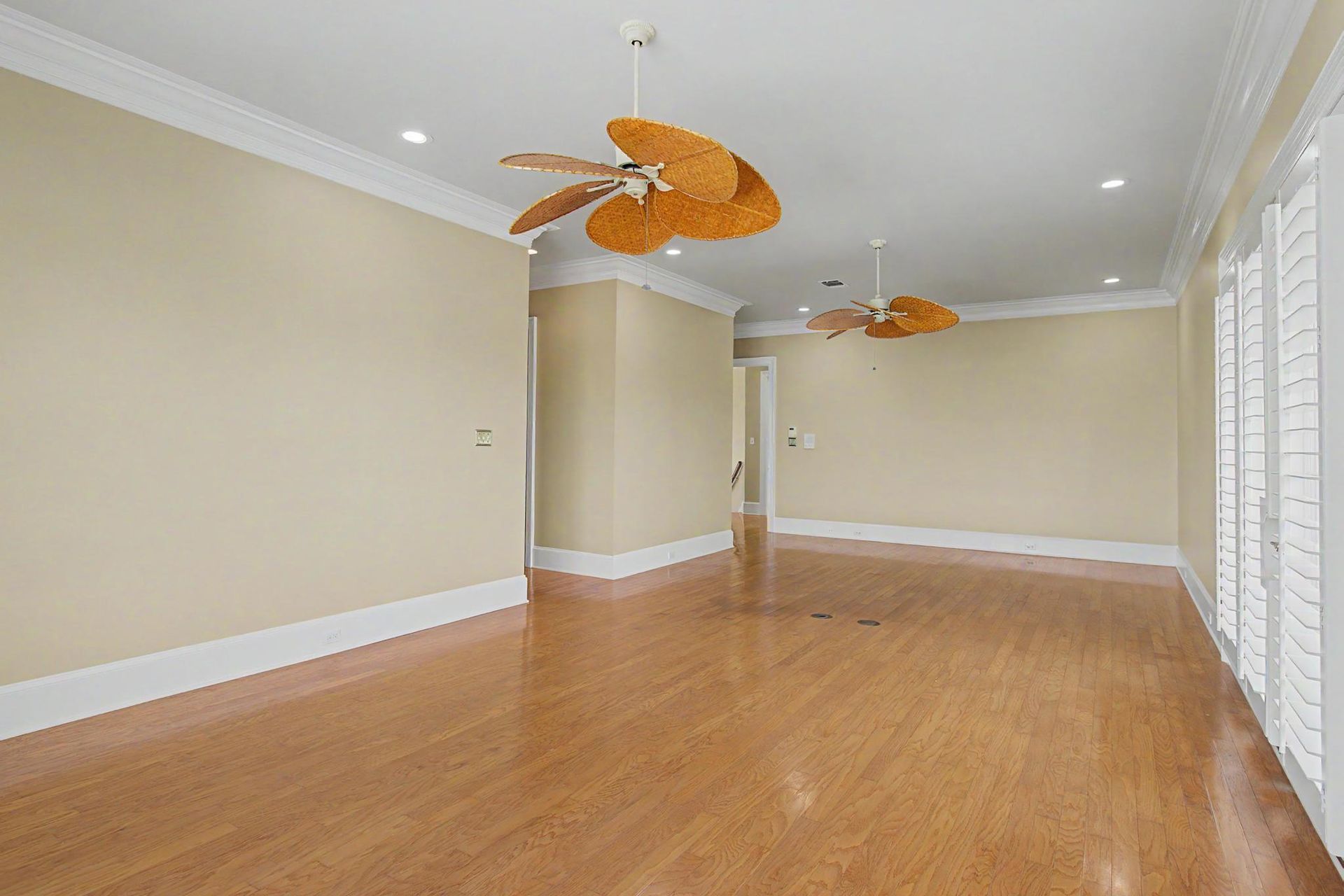 A second bonus room or upper living area with hardwood floors and tropical ceiling fans, light pouring in from windows on multiple walls