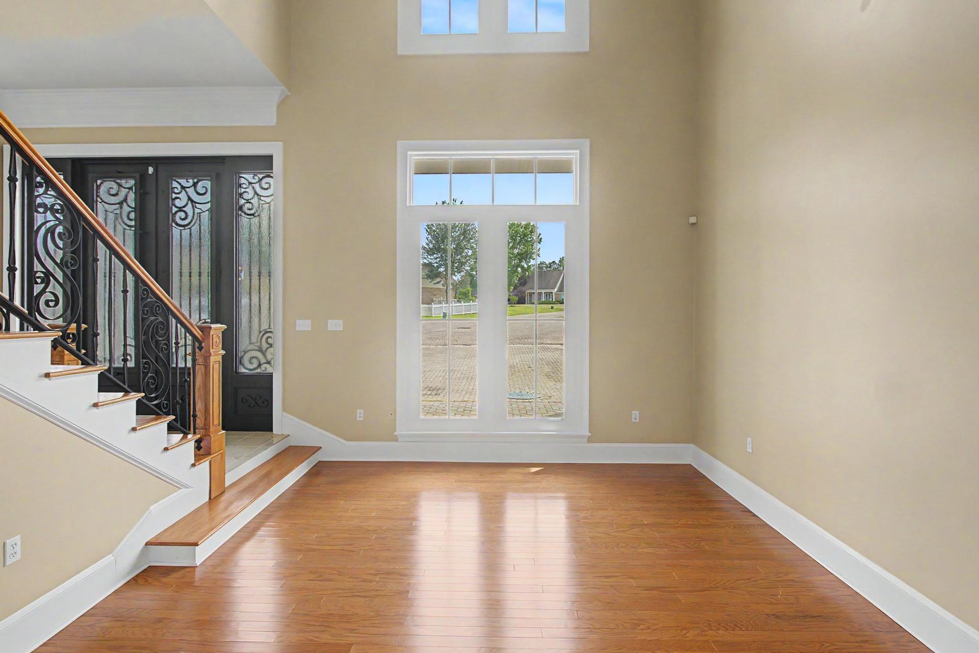 Two-story foyer of 19384 Leeward Cove, with custom wrought-iron entry doors, hardwood floors, and a tall arched window looking out onto the Windance community